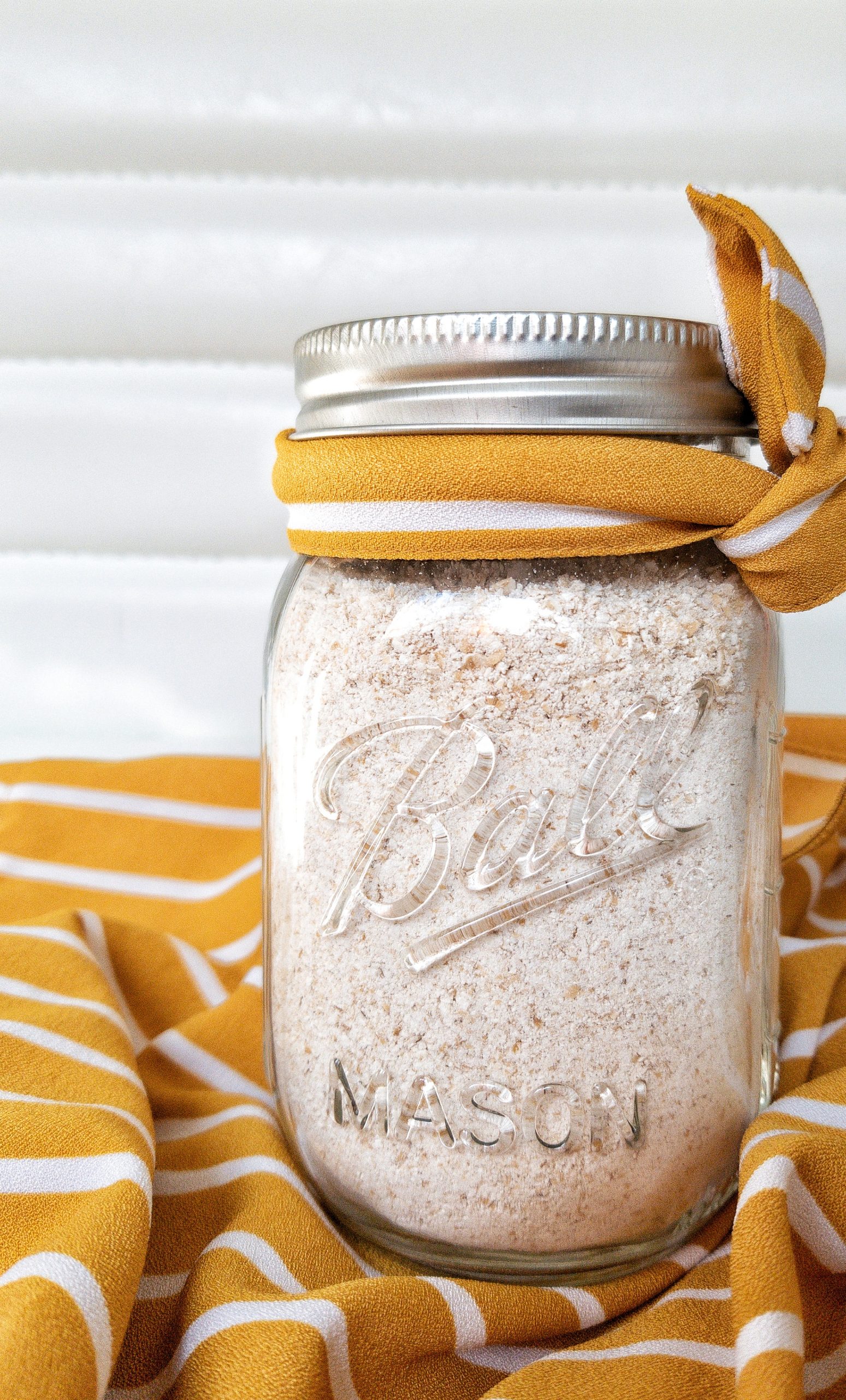 Oat flour in a glass mason jar tied with a yellow and white ribbon