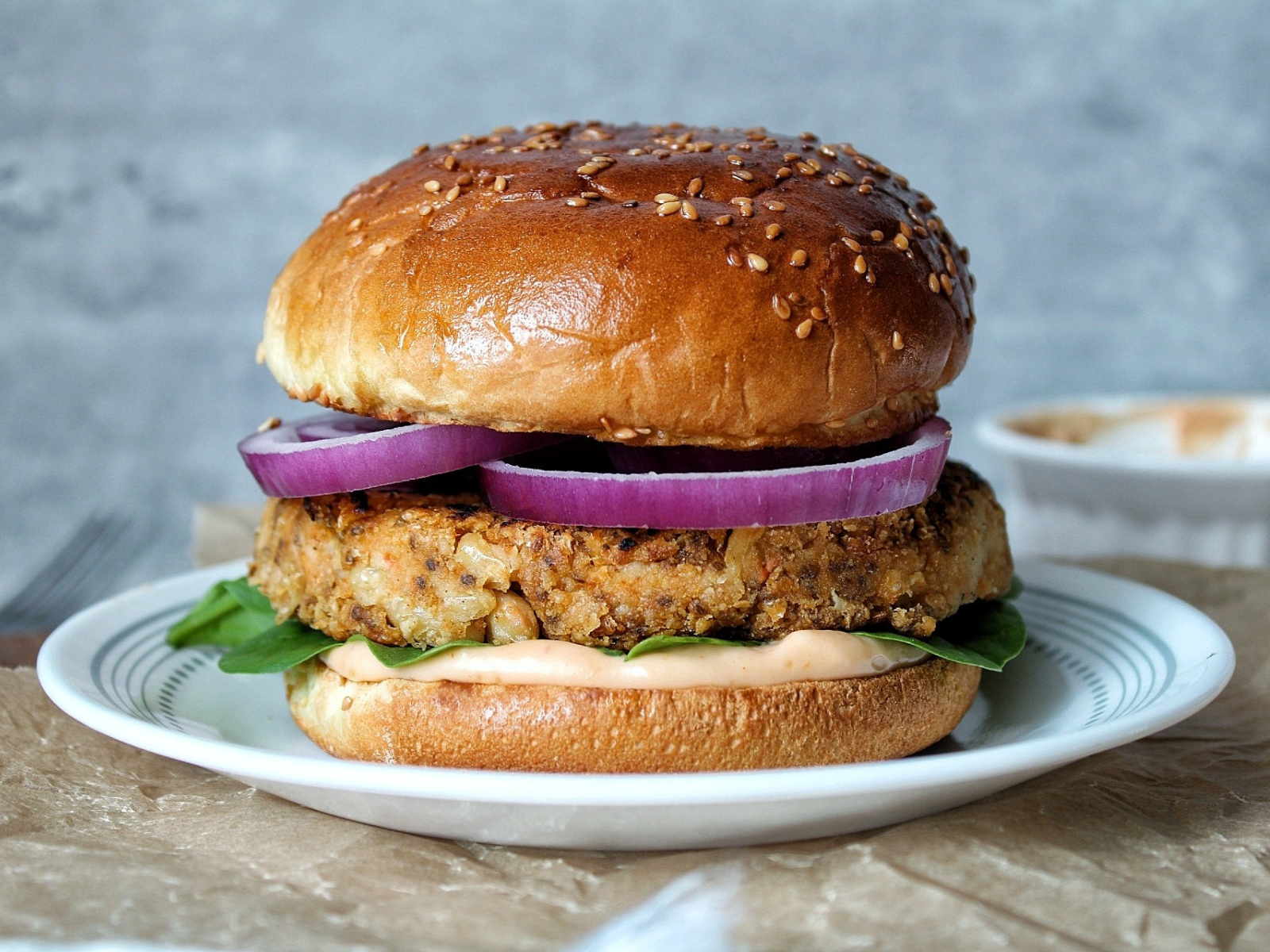 Cannellini bean burger with sirarcha mayo sauce, spinach, and sliced onions.