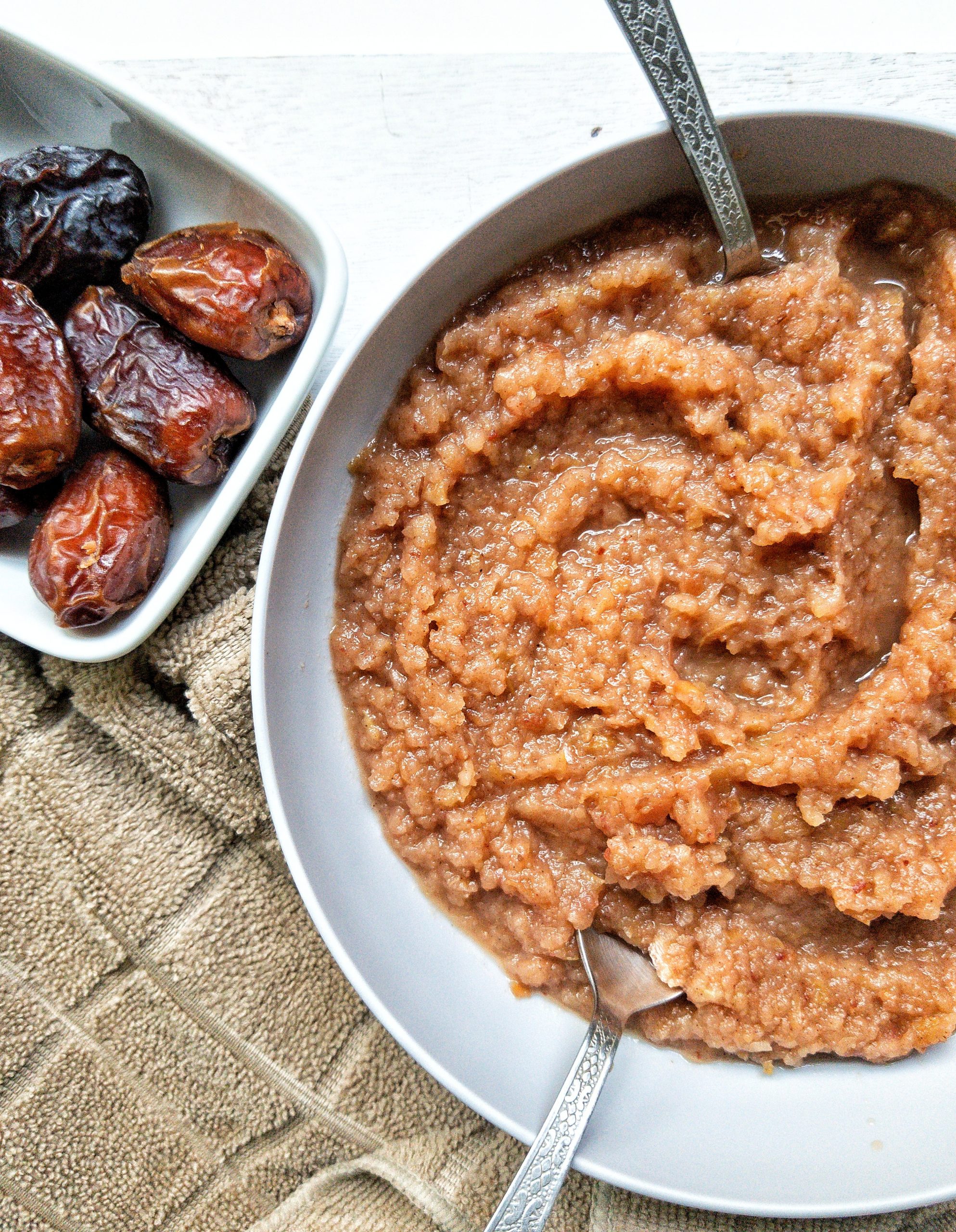 Homemade vegan applesauce in a large bowl with a side of dates