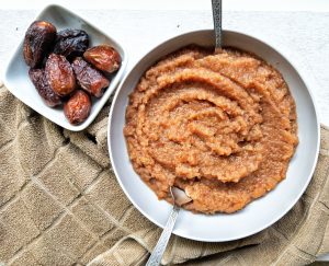 Homemade applesauce in a bowl with a side of dates