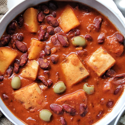 Habichuelas guisadas or Puerto Rican bean stew made with potatoes, beans, and green olives in a bowl.