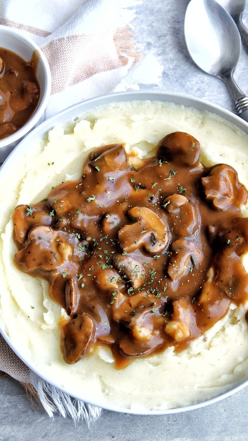 Oil-free mushroom gravy in a gray bowl filled with vegan mashed potatoes.