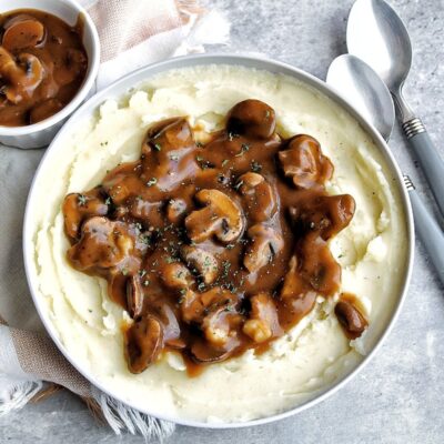 Oil-free mushroom gravy on top a bowl of creamy mashed potatoes.