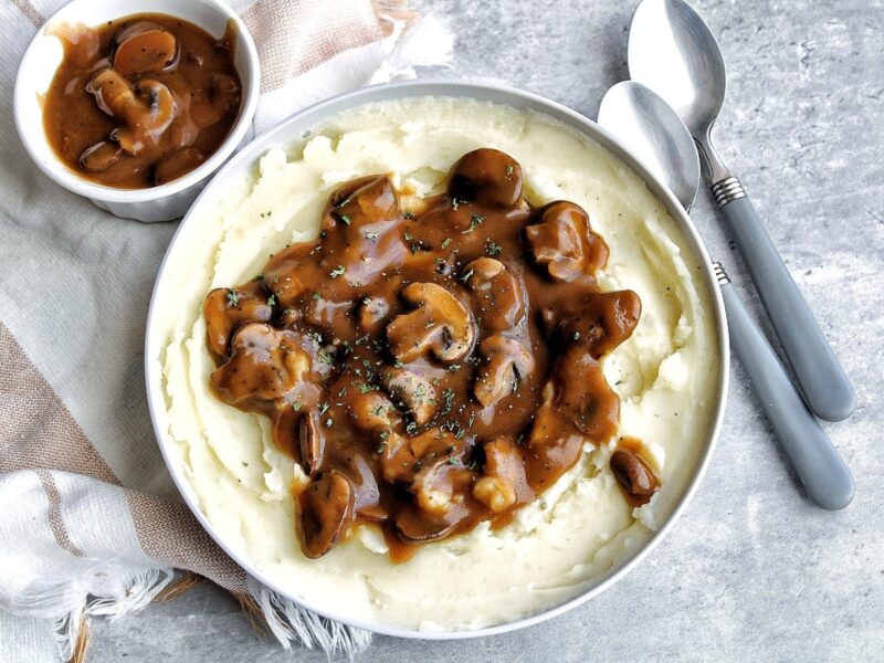Oil-free mushroom gravy on top a bowl of creamy mashed potatoes.
