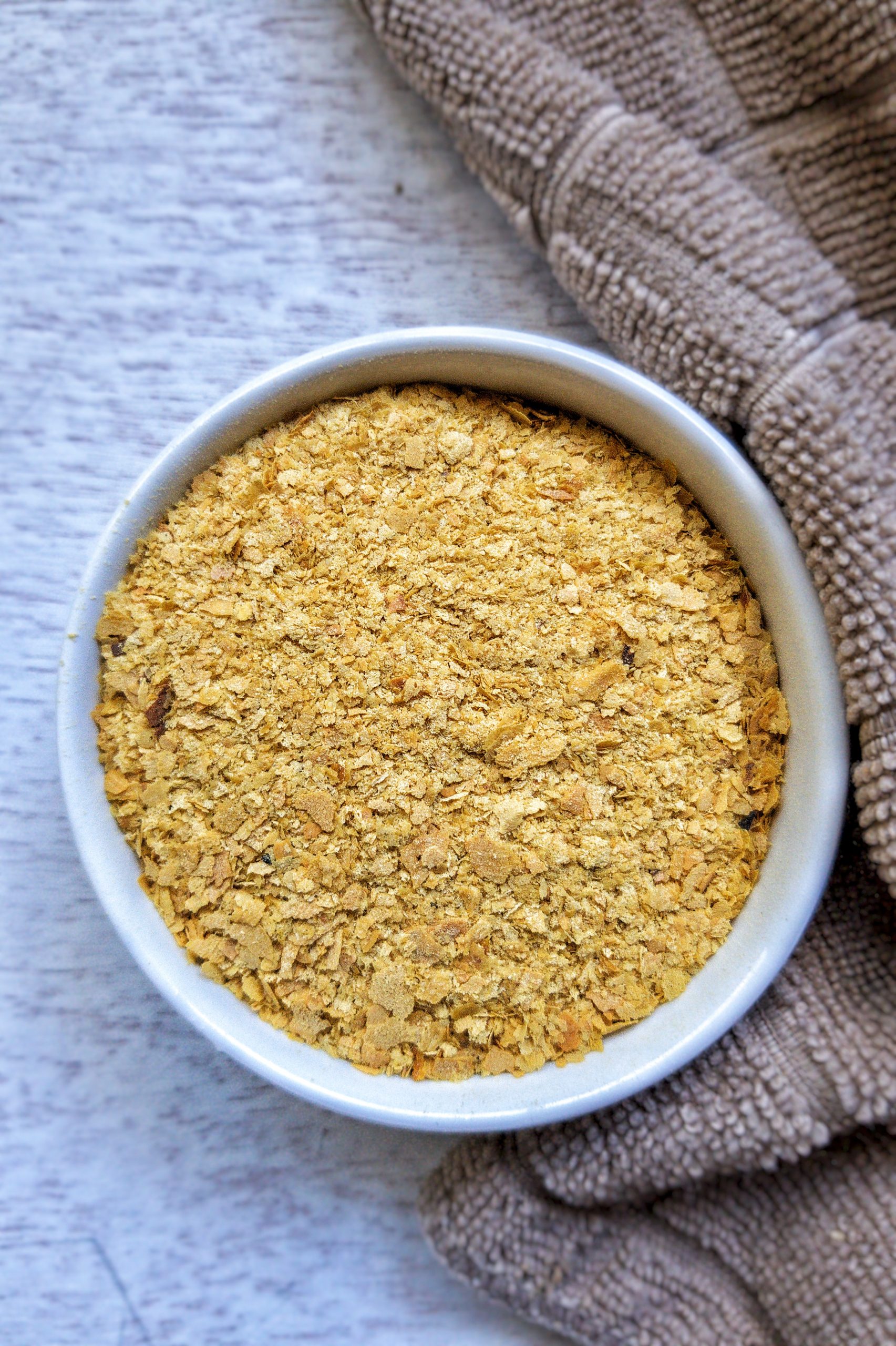 Nutritional yeast in a small, white bowl. 
