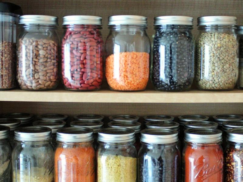 Mason jars in a pantry filled with dry legumes and spices
