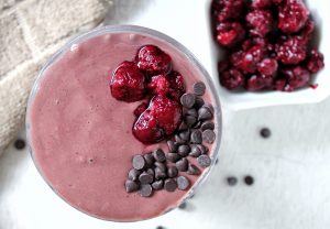 chocolate raspberry smoothie in a glass cup and side of raspberries
