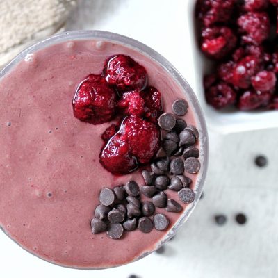 chocolate raspberry smoothie in a glass cup and side of raspberries