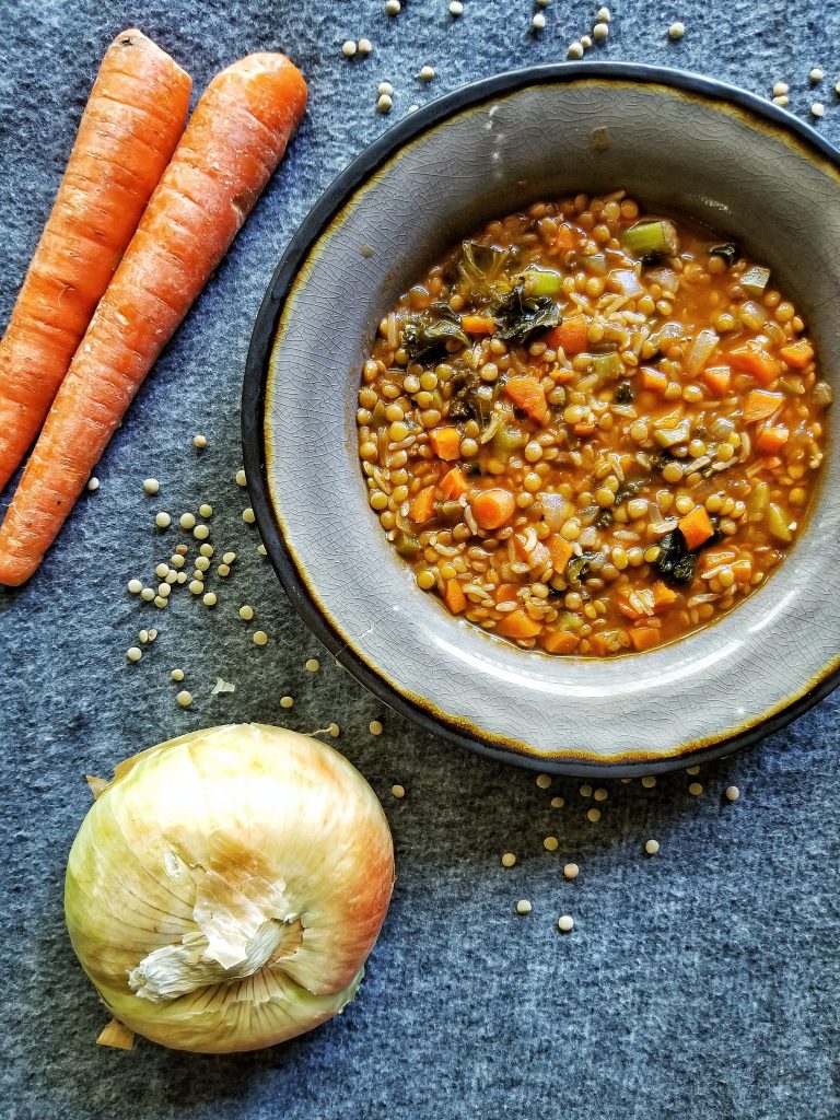 Gray bowl with lentil and veggies soup with carrots and onion photographed