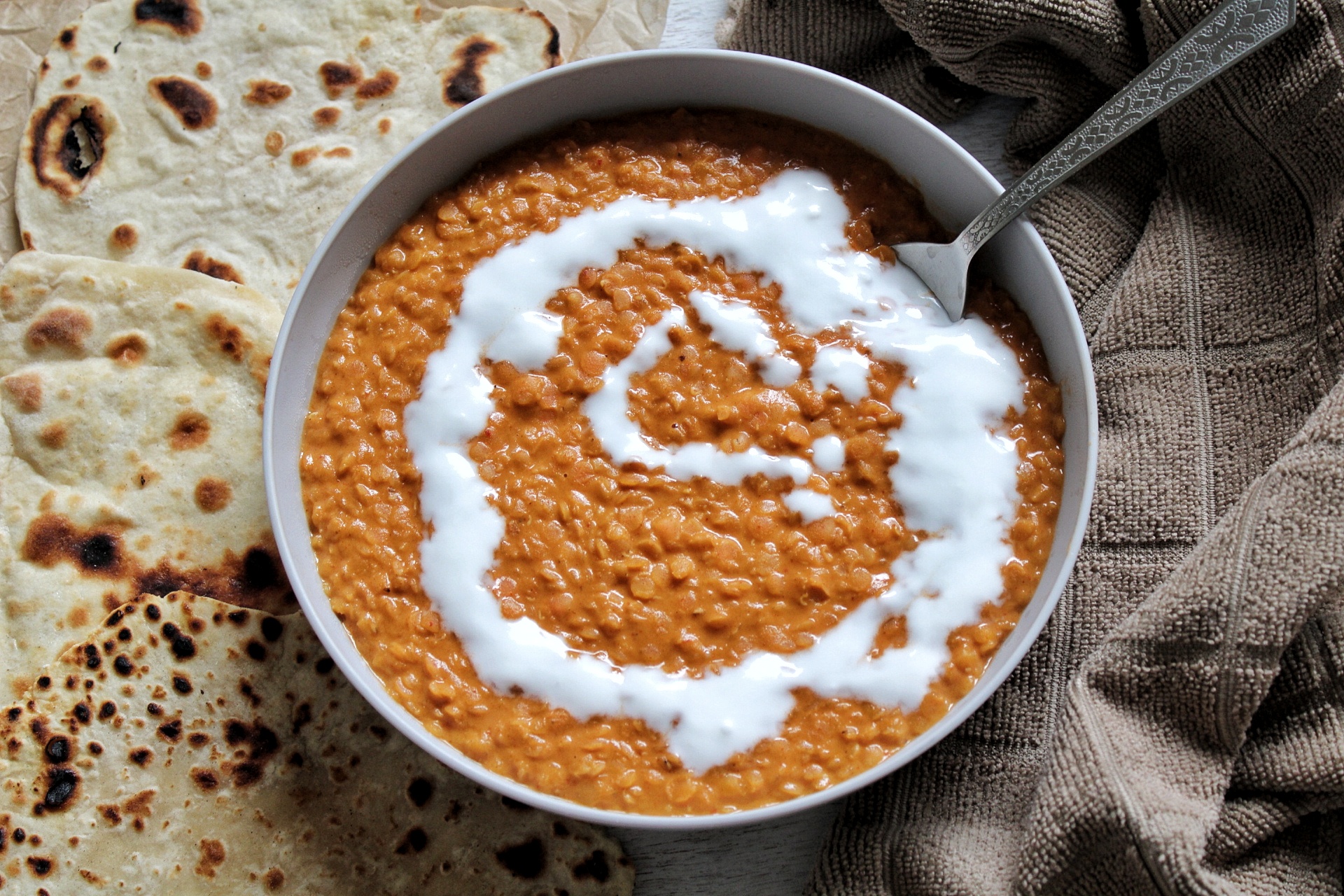 Peanut butter red lentil curry topped with coconut milk and a side of flatbread.