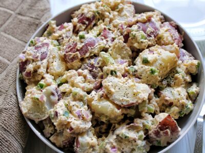 Creamy potato salad with cashew sauce, onion, and bell pepper in a bowl.