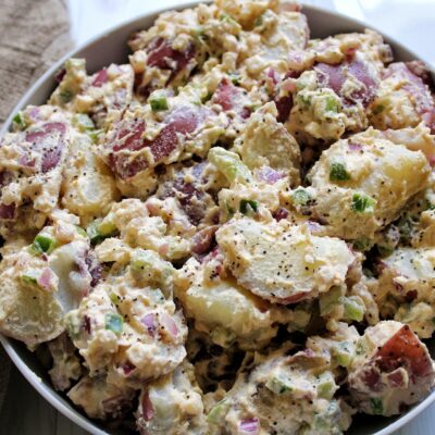 Creamy potato salad with cashew sauce, onion, and bell pepper in a bowl.