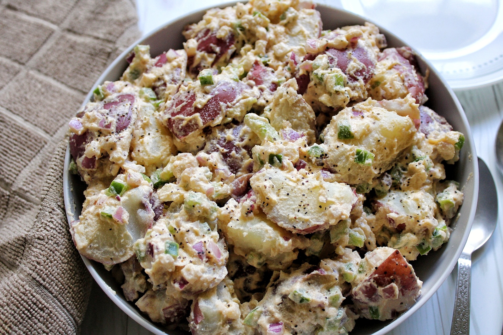 Creamy potato salad with cashew sauce, onion, and bell pepper in a bowl.