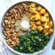 Oat bran in a gray bowl topped with walnuts, kale, tofu, vegan butter, and red chili pepper