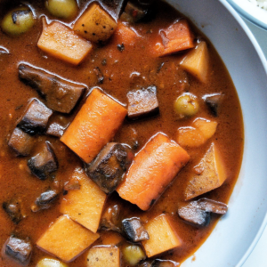 Puerto Rican vegan beef stew or "carne guisda" in a grey bowl with a side of white rice.