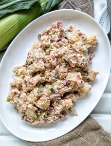Summer vegan potato salad made with a creamy cashew sauce, onion, bell peppers, and spices.