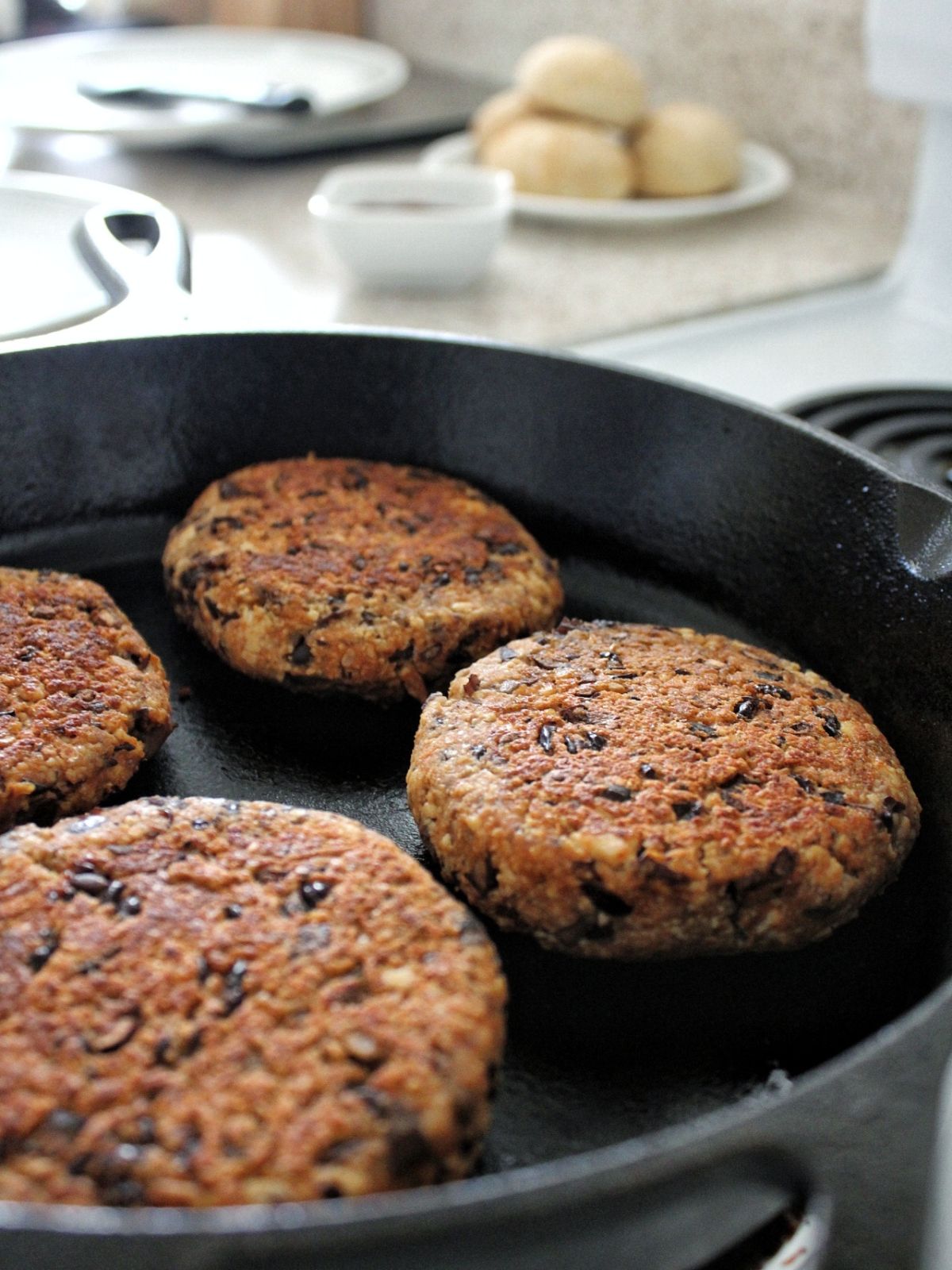 Vegan tofu black Bean Burgers frying in a cast-iron pan. 