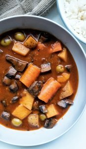 Puerto Rican vegan beef stew or "carne guisda" in a grey bowl with a side of white rice