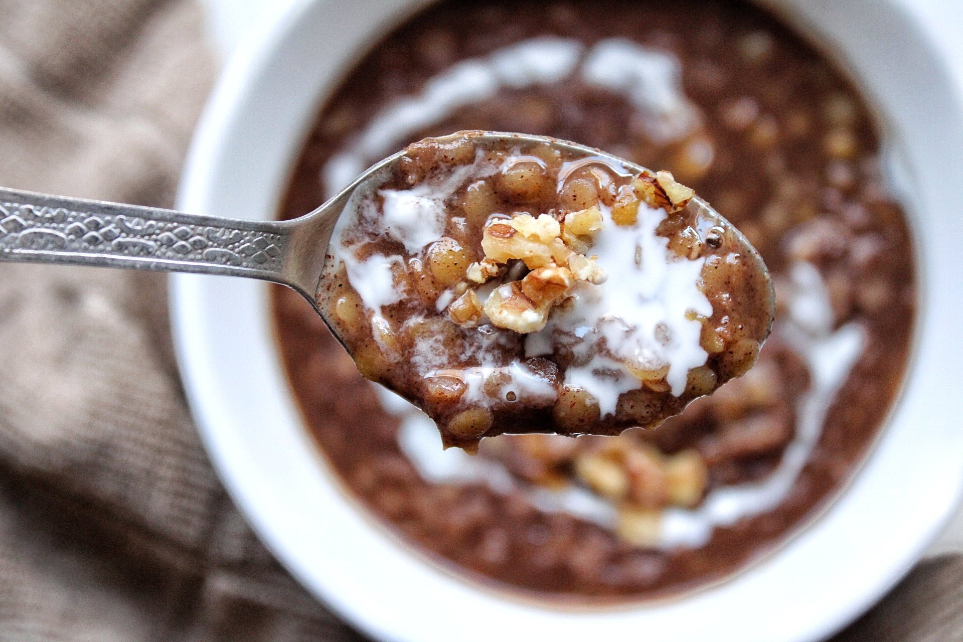 Creamy morning lentils closeup with walnuts in a spoon with a splash of coconut milk. 