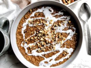 Sweetened, cooked red split lentils with a drizzle of coconut milk and crushed walnuts in a bowl.