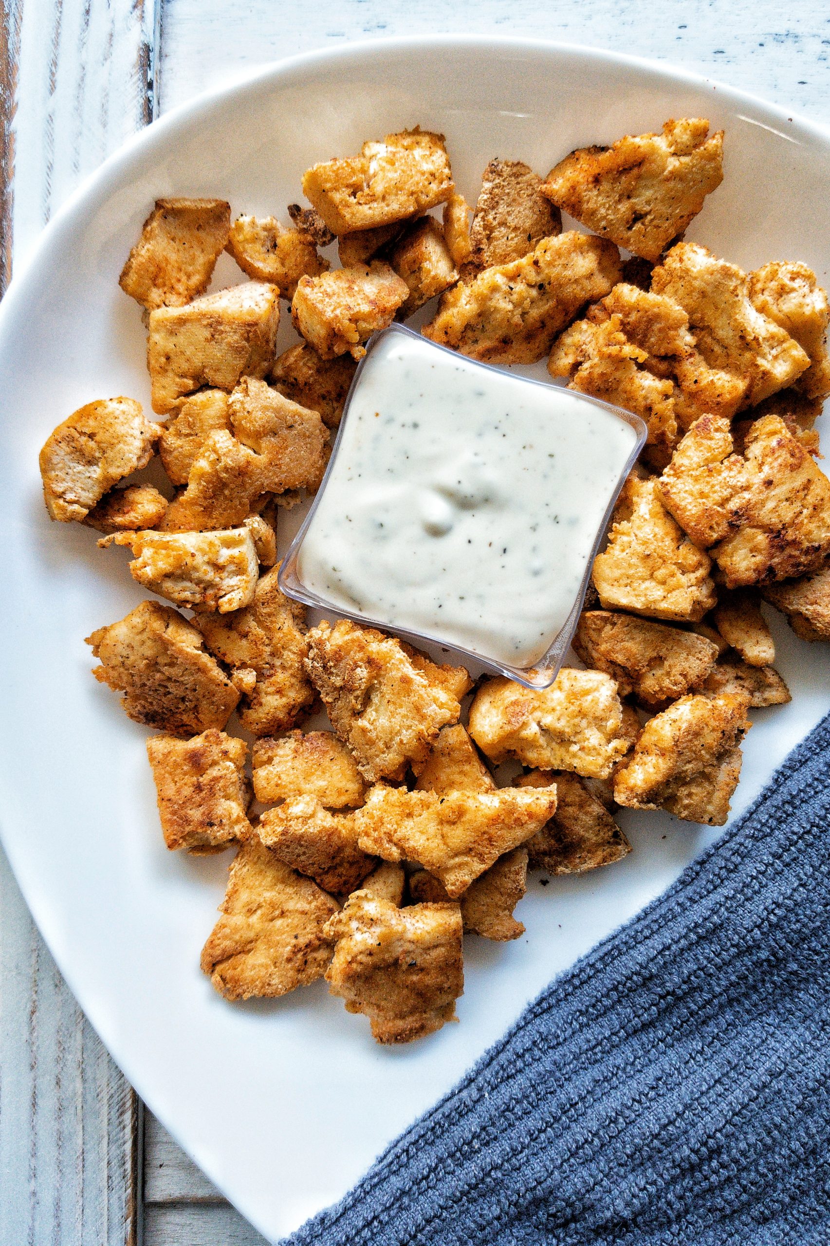 Tofu nuggets on a platter with a white dipping sauce placed in the middle 