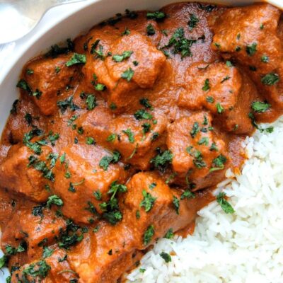 Tofu butter chicken or murgh makhani topped with chop cilantro. With a side of rice.