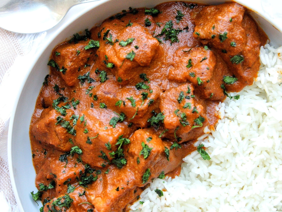 Tofu butter chicken or murgh makhani topped with chop cilantro. With a side of rice.