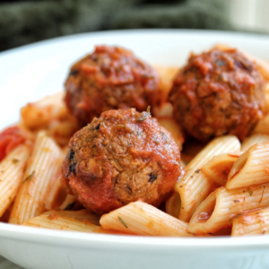 Vegan lentil meatballs tossed in sauce and served with penne pasta