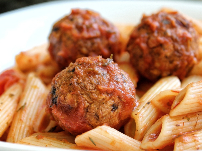 Vegan lentil meatballs tossed in sauce and served with penne pasta