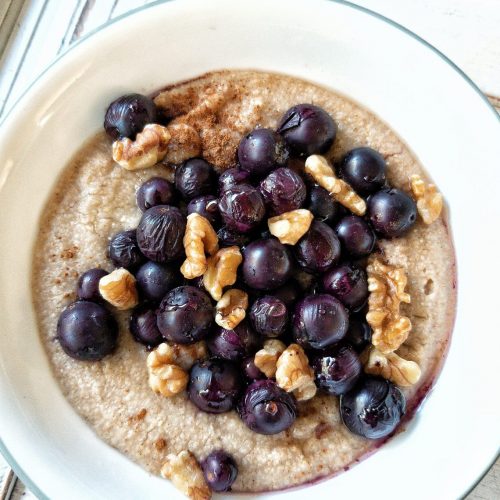 Bowl of creamy oat bran topped with grapes and walnuts