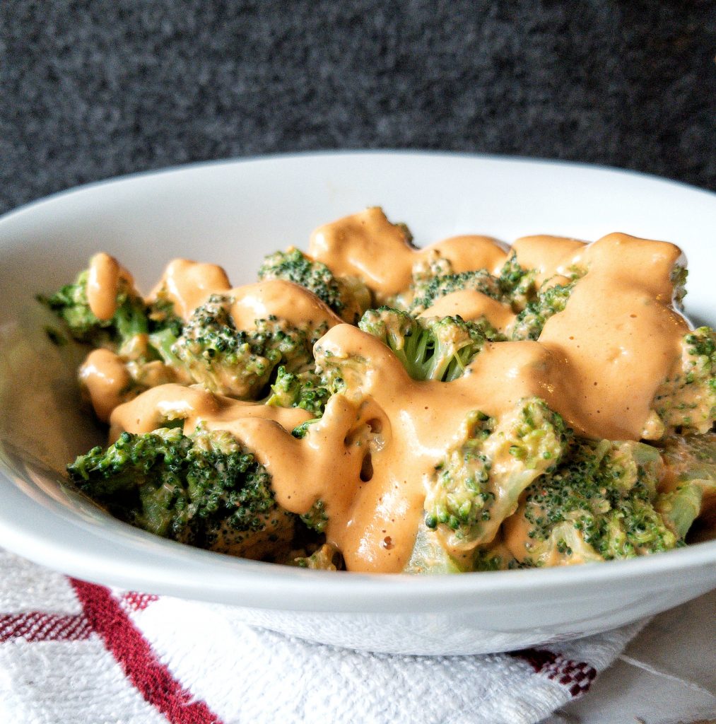 Plant-based, non-dairy cheese sauce poured over cooked carrots 