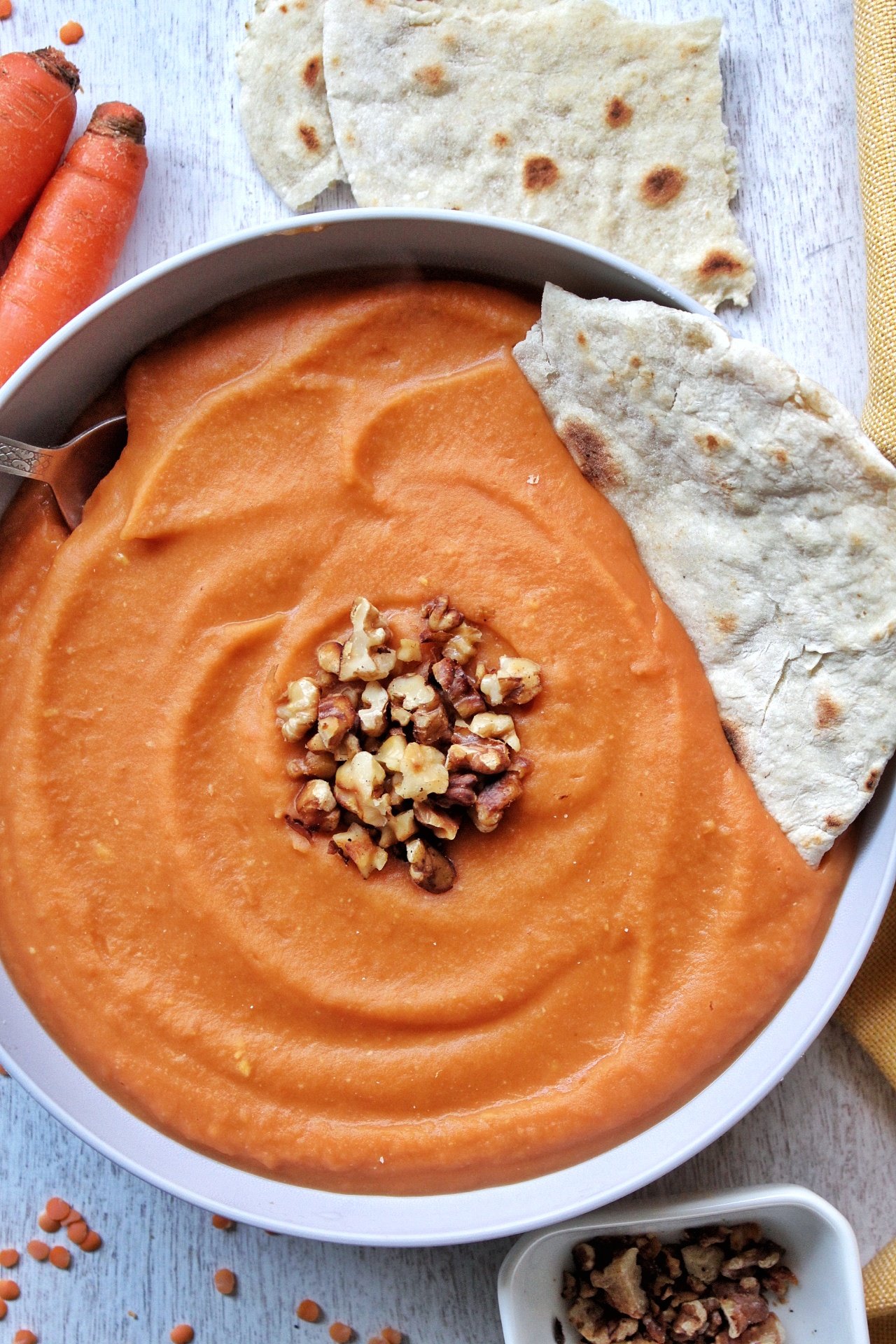 Bowl of red lentil carrot soup with a side of homemade flatbread 