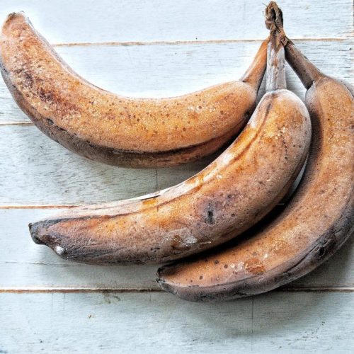 Three frozen bananas against a blue-white wooden background