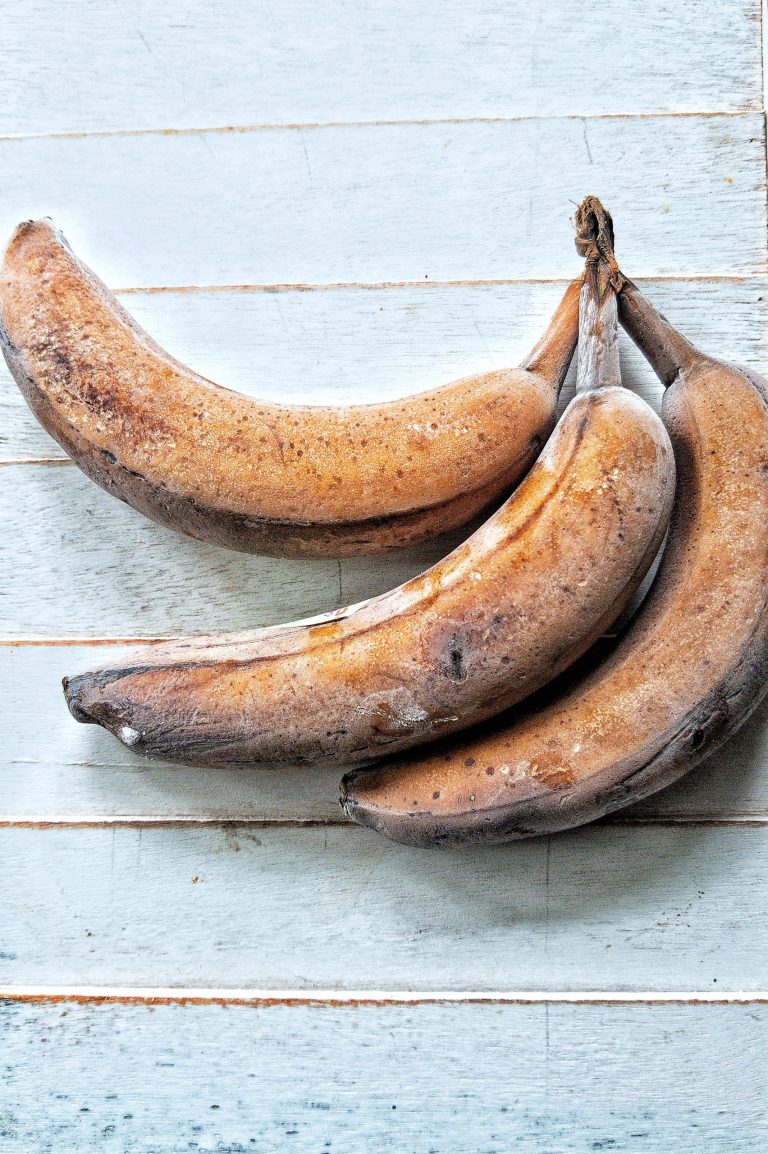 Three frozen bananas against a blue-white wooden background