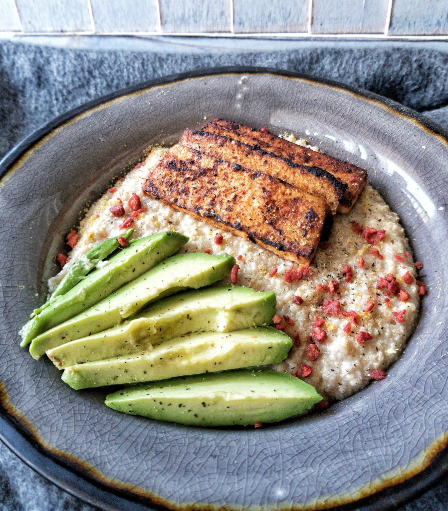 Gluten-free, savory, vegan oat bran bowl topped with avocado slices and tofu