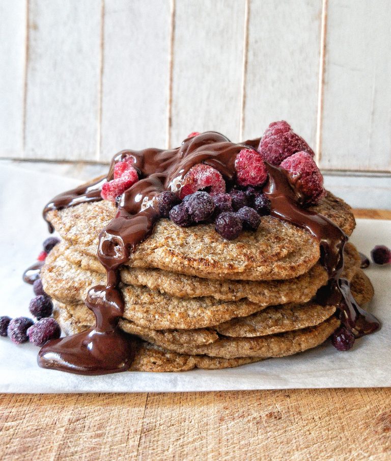Less or fewer than 10 ingredients gluten-free chocolate oat bran pancakes topped with berries and a homemade chocolate sauce