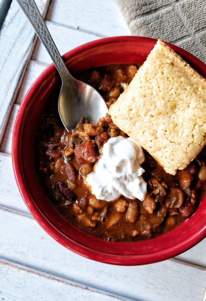 Bowl of vegan mushroom chili with vegan sour cream and cornbread