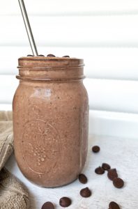 Chocolate peanut butter smoothie in a glass mason jar topped with chocolate chips