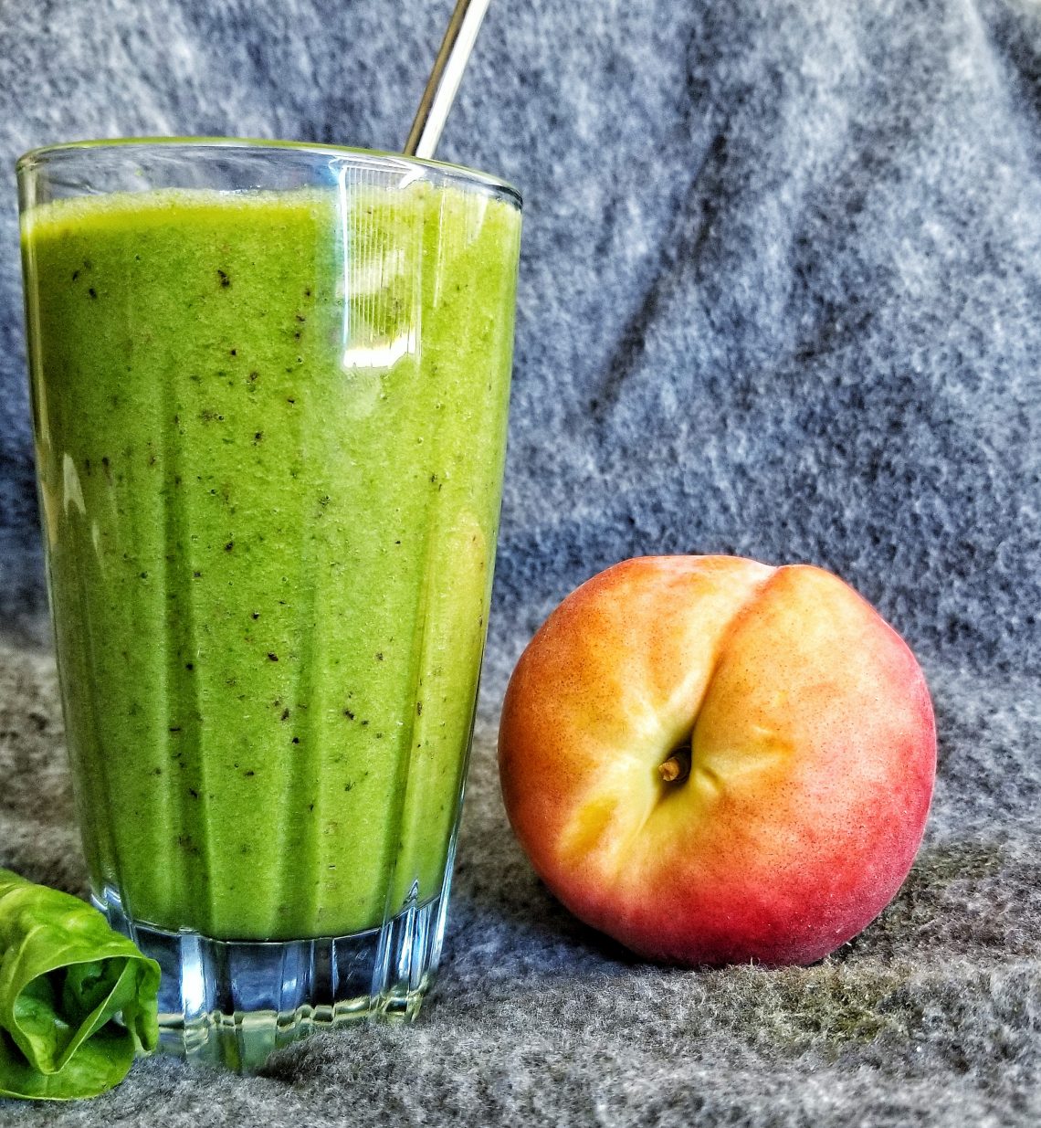 Green smoothie with frozen fruit including peaches and bananas.