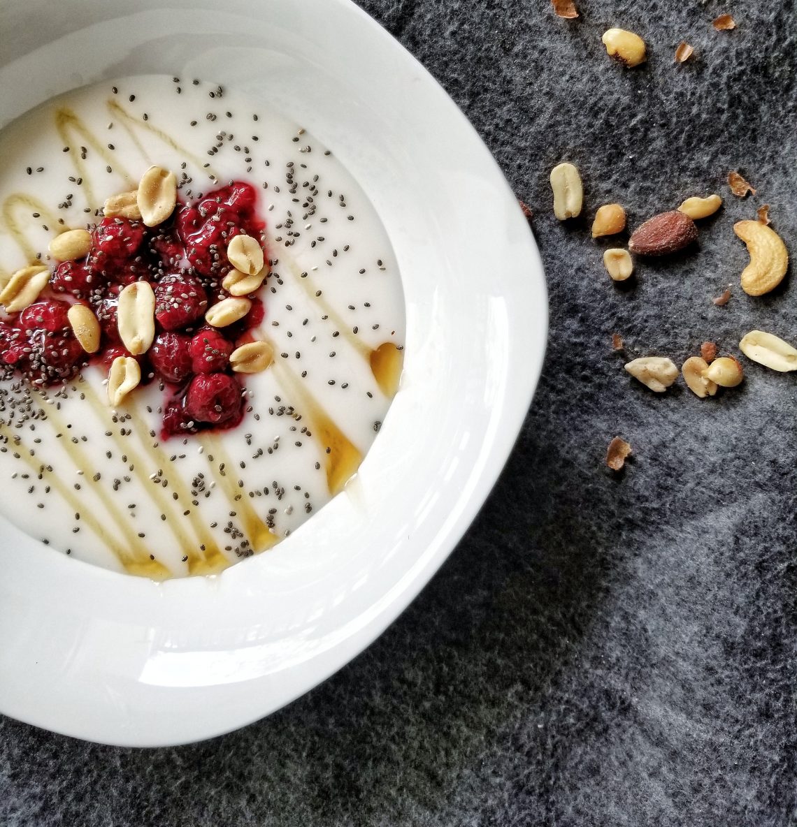 Vegan yogurt with frozen raspberries, nuts, and honey.