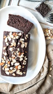 A loaf of vegan, gluten-free double chocolate banana bread topped with sliced almonds