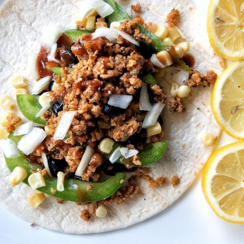 Flour tortilla topped with vegetables and walnut meat with a side of sliced lemon