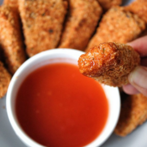 Close up extra crispy nuggets with a honey hot sauce.