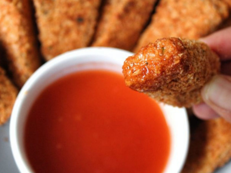 Close up extra crispy nuggets with a honey hot sauce.