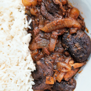 Stewed mushrooms with onions on a plate with a side of rice.