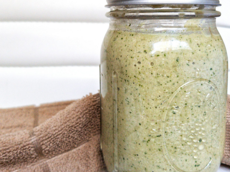 Green, creamy cilantro sauce in a clear glass canning jar.