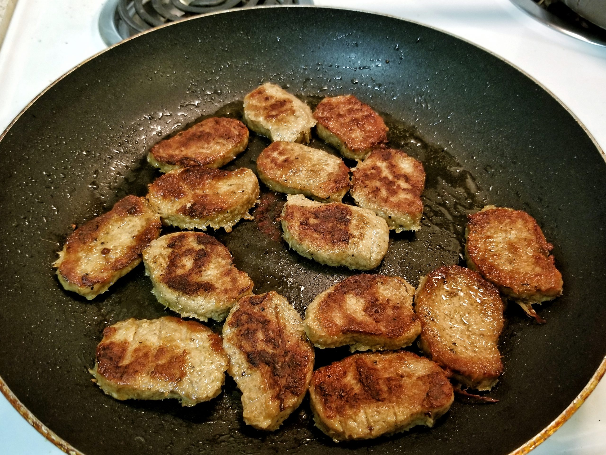 Mock meat nuggets cooking in a large non-stick pan