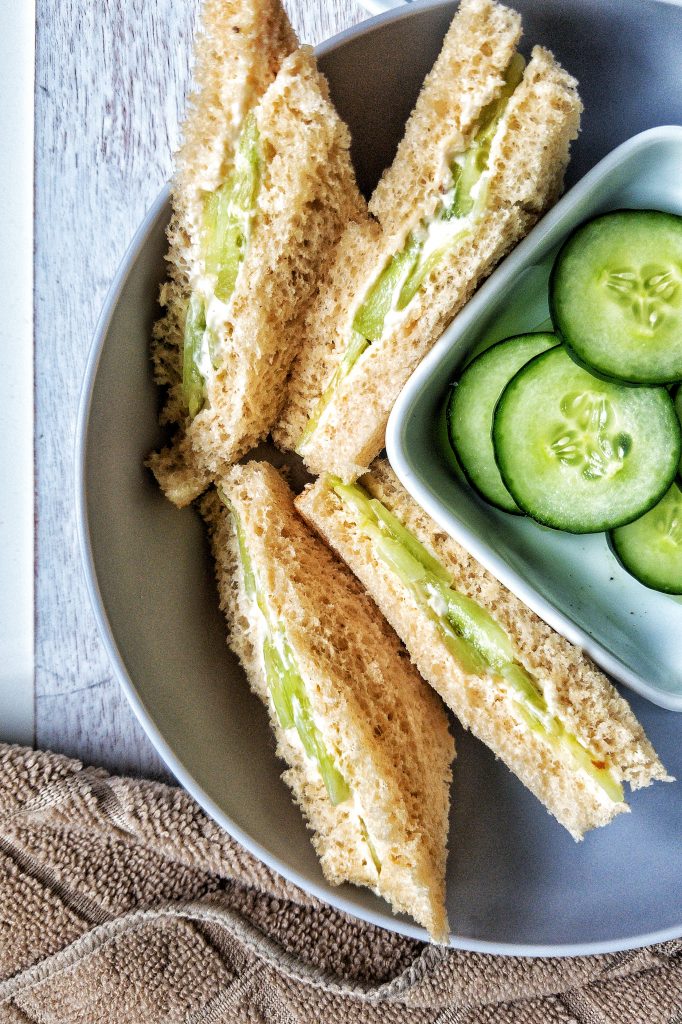 Closeup of cucumber tea sandwiches with a side of sliced cucumbers