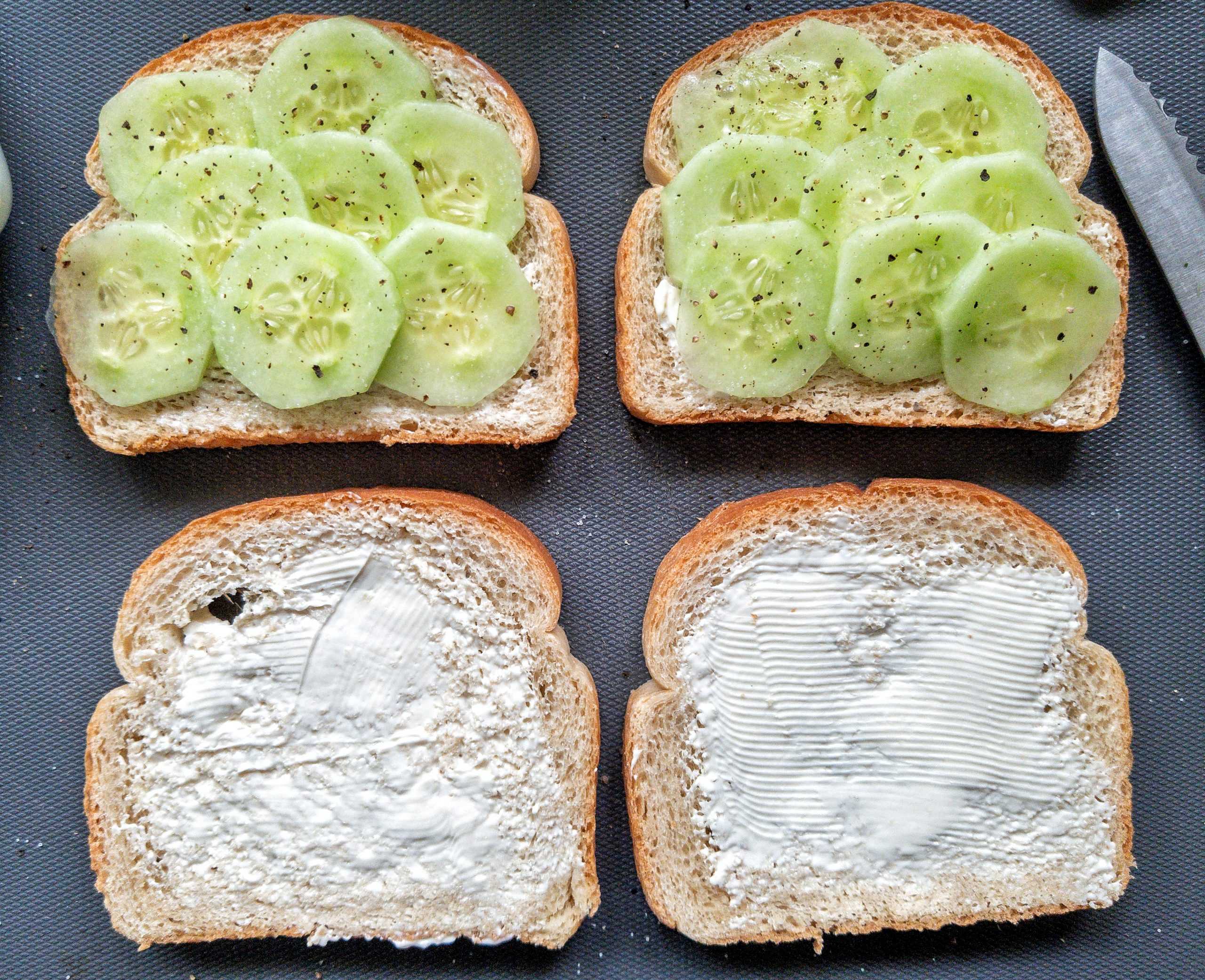 Four slices of buttered, white bread. Two slices with sliced cucumber, salt, and ground black pepper 