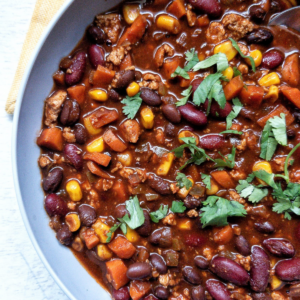 Vegetarian tofu bean chili in a gray bowl topped with chopped cilantro